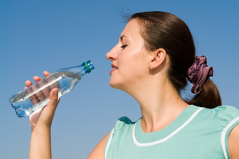 beautiful woman drinks water on a blue sky