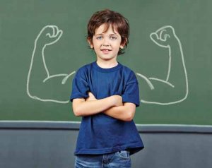 Strong child with muscles drawn on chalkboard in elementary scho